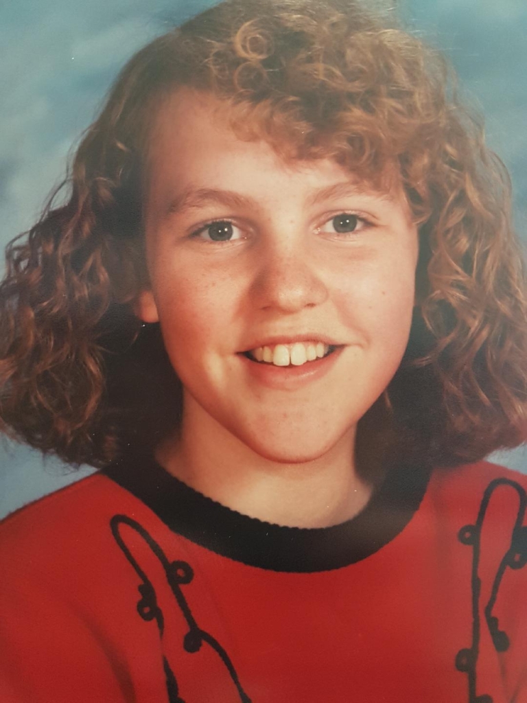 Ardra in her grade 8 school picture. She has an aggressive perm and hasn't yet grown into her buck teeth. These are the awkward years.