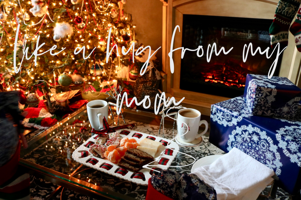 A Christmas tree in the background with a plate of treats including fruitcake in the foreground. The words Like a hug from my mom are written across the photo.