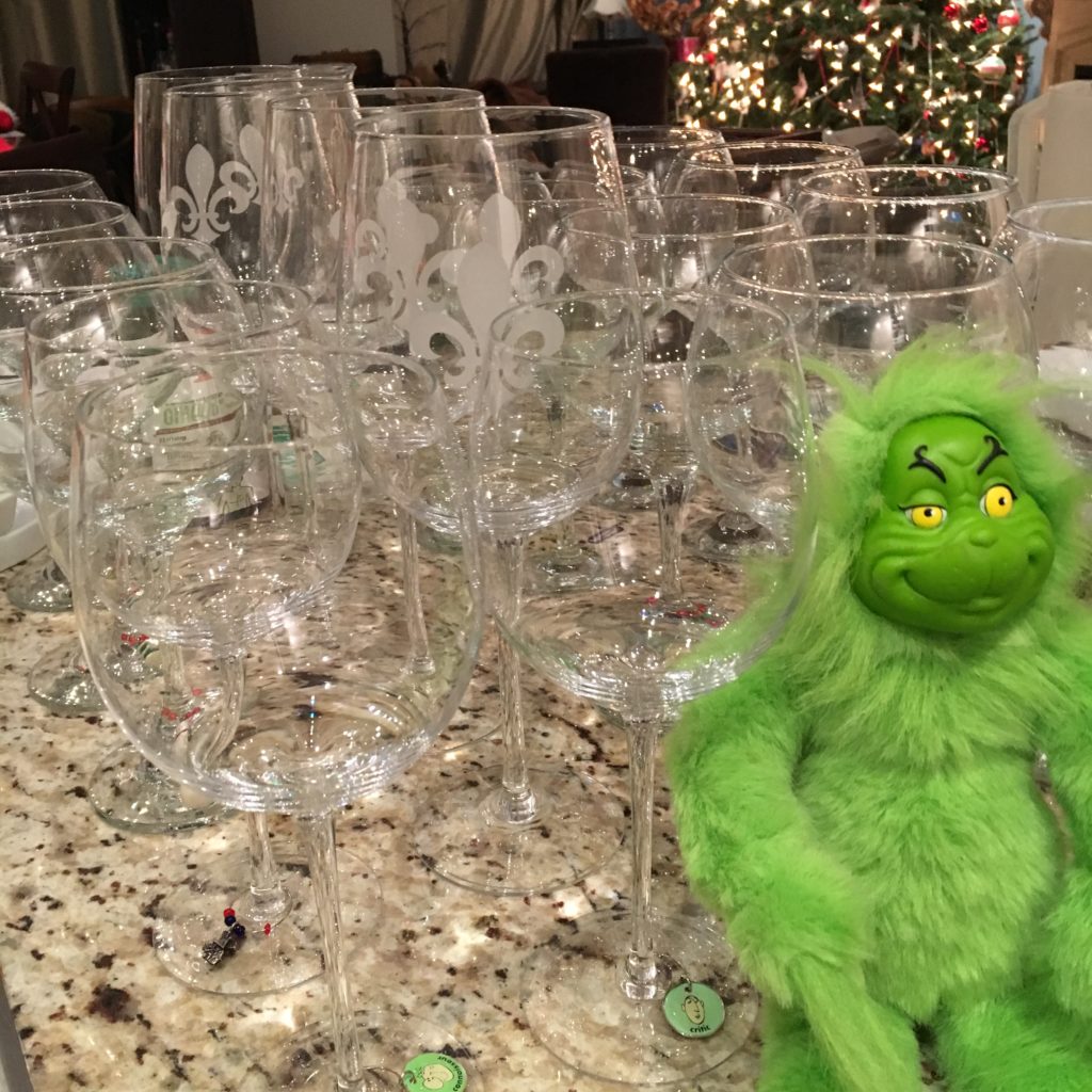 Empty wine glasses sit on a counter next to a toy Grinch.