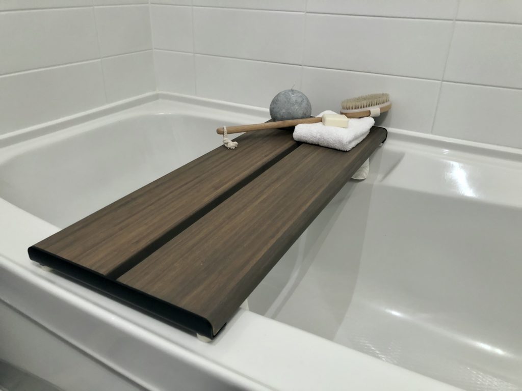 A white soaker tub with a dark wooden bench makes a great gift for a person with MS.
