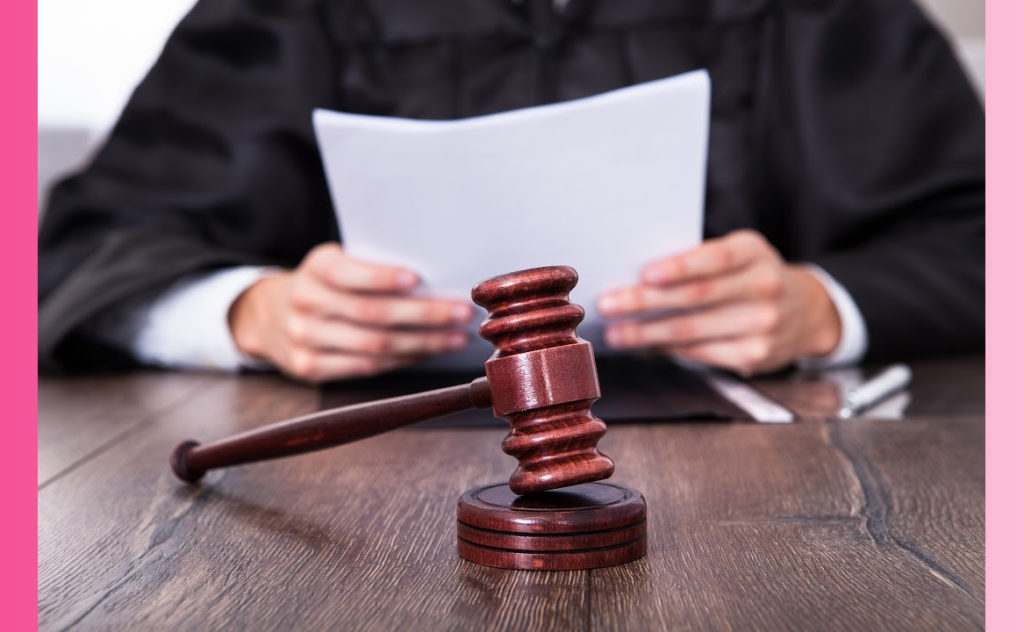 A judge sits behind a gavel, reviewing paperwork. 