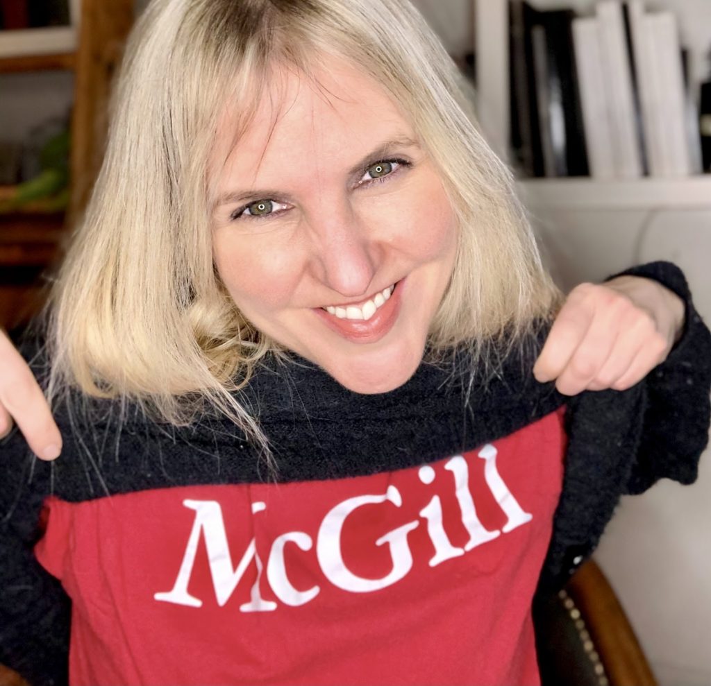 A woman lifts up her sweater to reveal a McGill T-shirt that she wore to remind herself that despite having some MS-related cognitive dysfunction she is still able to learn.