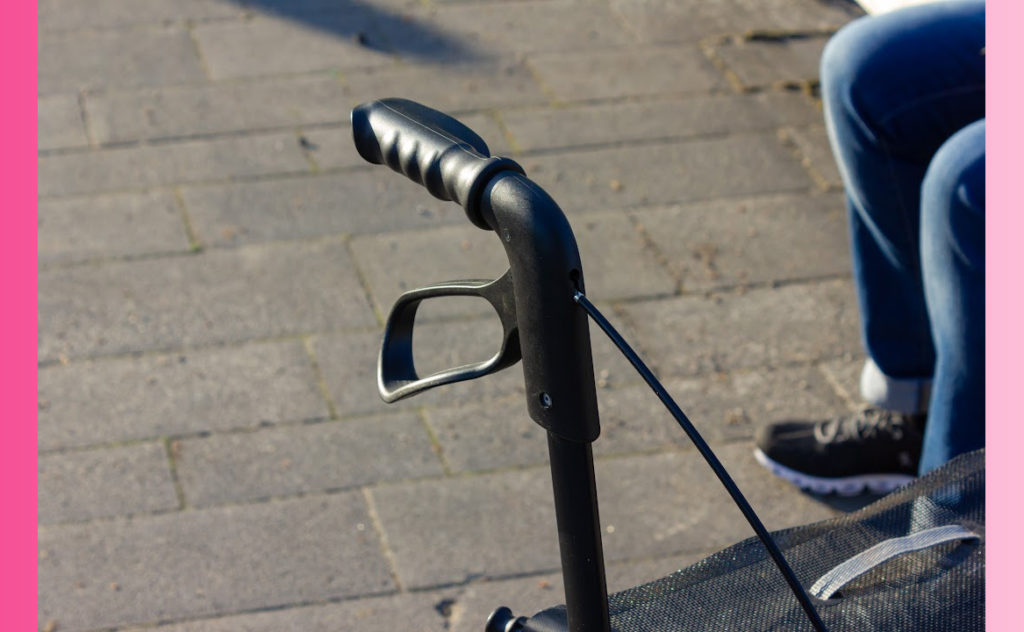 a portion of a rollator walker next to a pair of legs